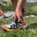 Sportista veže trail running patike na planinskoj stazi tokom ljetnog outdoor treninga u prirodi.
